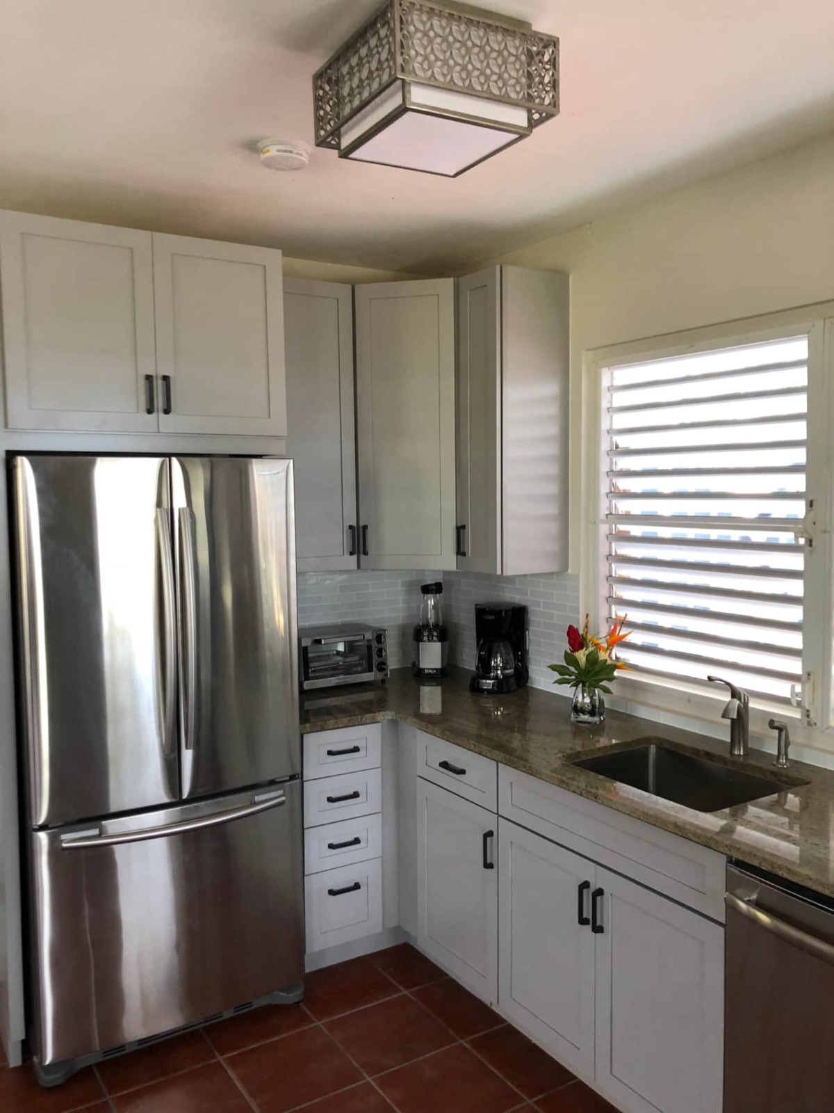 Chef's kitchen with granite counters, stainless steel refrigerator and tropical flowers